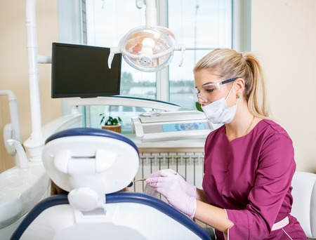Female dentist in dental office treats teeth with kid patient. Indoorの写真素材