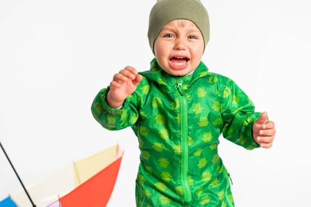 Little baby boy crying in the studio near umbrella. Isolated on the white background