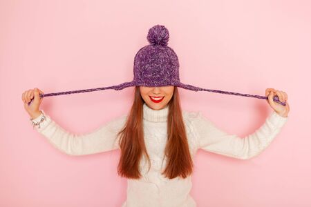 Fashion happy young woman in knitted hat and sweater having fun over pink background. Smiling. Red lipsの写真素材