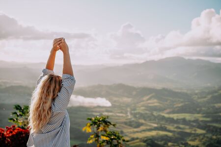 Beautiful view of young woman enjoying the sun on top of the mountain on the dawn. Great landscape....