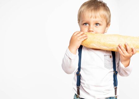 Funny baby boy eating a loaf of bread in studio. Isolated on white background. Tasty and fresh food. Bakery productsの写真素材