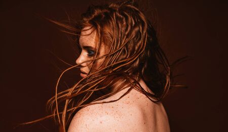 Woman with flying red dreadlocks hairstyle posing in studio. Blue glittered make-up. Smokey eyes. Isolatedの写真素材