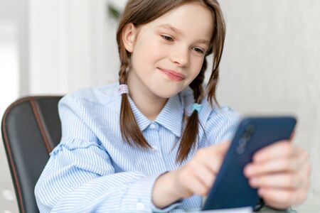 Young girl using smartphone while sitting at home.