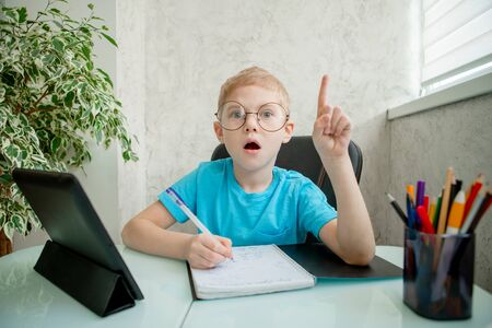 Young boy learn by tablet at home. Distance learning in quarantine. Isolation. Homework. Online...