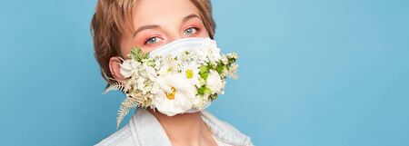 Face mask design with flowers. Portrait of beautiful woman with blue eyes, fashion make-up and mask over blue backgroundの写真素材