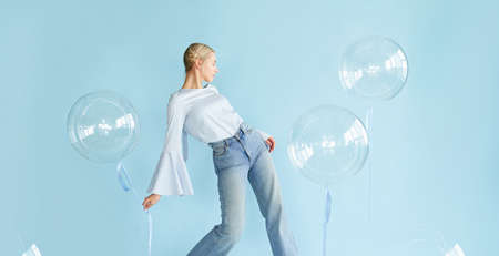 young blonde woman posing in studio with transparent balloons. Concept dreaming