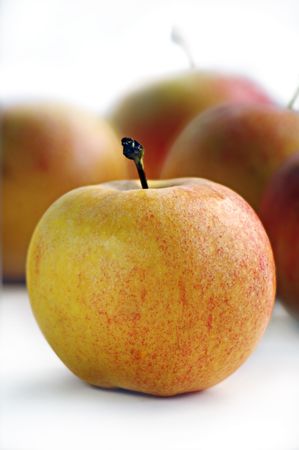 Yellow apple against several red applesの写真素材