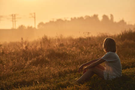 Pretty young woman in field at sunsetの写真素材
