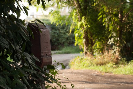 An old abandoned mailbox in Russian village. With countryside road and landscape at the background.の写真素材