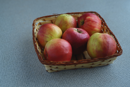 Red juicy apples in the basket on the tableの写真素材