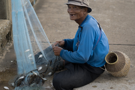 July 12 2017 - Chantaburi ,Thailand - Old Fishermen clearing fisherman net , a lot of small fish