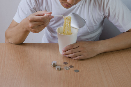 Freelance man not have salary, stressed out in the end of mouth ,eat instant noodles.の写真素材