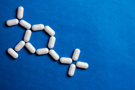 Molecule model made of pills. Medical concept of drug formula on blue paper background.の写真素材