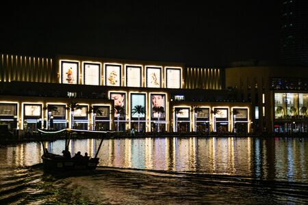 DUBAI, UAE - NOVEMBER 8, 2018: A tourist traditional boat sailing in Dubai fountain lake near luxury Dubai Mall in downtown at nightのeditorial素材