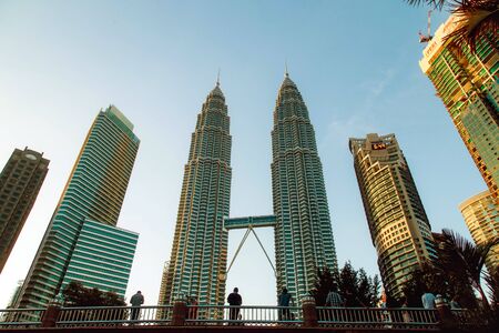 KUALA LUMPUR, MALAYSIA - NOVEMBER 9, 2018: Tourists looking at Petronas Twin Towers in Malaysian capital standing on a bridge filled with people next to Suria KLCC shopping mall in downtown at dusk.のeditorial素材