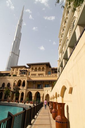 DUBAI, UAE - NOVEMBER 13, 2018: Tourist walking nearby Burj Khalifa tower and Souk al Bahar lor rise apartment buildings near Dubai fountain lake and poolのeditorial素材