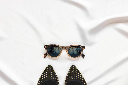 Women's shoes and accessories: glasses on a light background. Top view. Stylish party accessories.