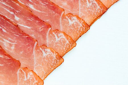 amon slices on white background. Traditional Spain meat background. Spain ham on white wooden...