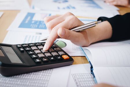 Businesswoman working on calculator to calculate business data the financial report on table.の写真素材