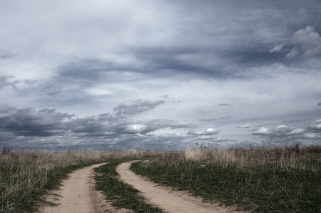 Beautiful rural field road and the cloudy skyの写真素材