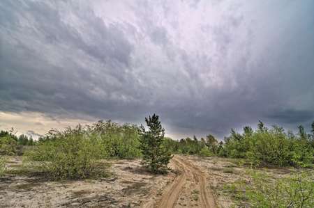 Country sandy road and cloudy stormic sky