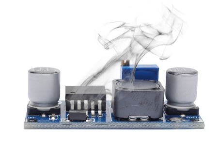 The electronic voltage stabilizer smokes from overheating. Isolated on white.