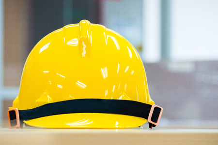 Yellow safety hard hat with black bar lay on table with blurry backgroundの写真素材