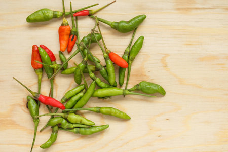 Small red and green chilli on wood chopping block.の写真素材