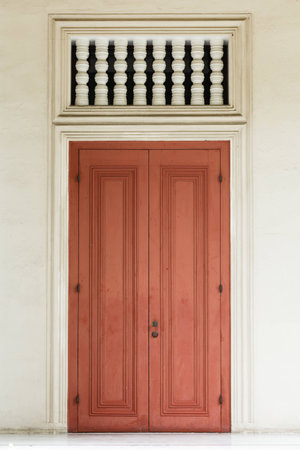 Ancient red door with white door frame and air passage.の写真素材
