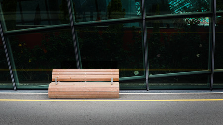 Round designed wooden bench with glassed building in backgroundのeditorial素材