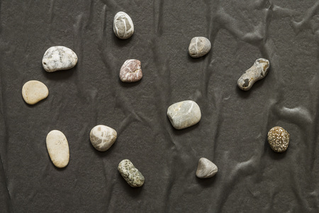 Several stones in a chaotic manner lie on a dark background. Abstraction, daylight.