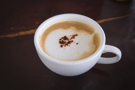 cappuccino coffee in white cup on wooden backgroundの写真素材