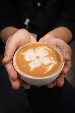Barista giving a coffee with flower floatingの写真素材