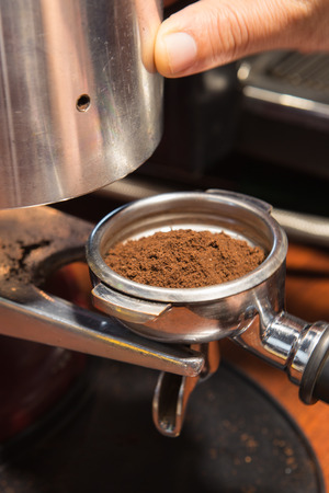 Freshly ground coffee beans by Grinder machine  in a  metal filterの写真素材