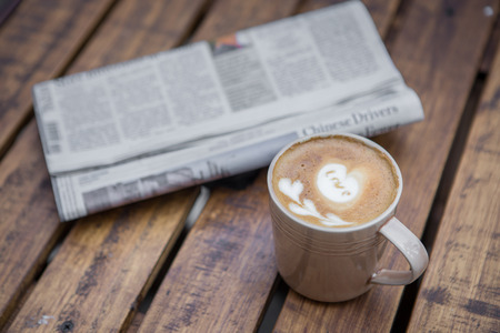 A newspaper and a cup of coffee on a wooden tableの写真素材