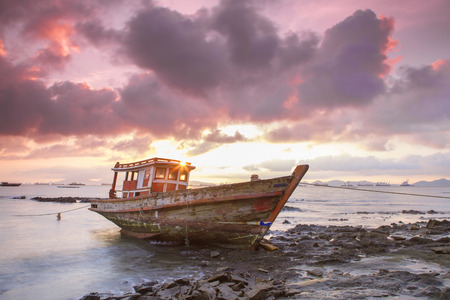 Abandoned fishing boat with beautiful sunset in the east, Thailandの写真素材