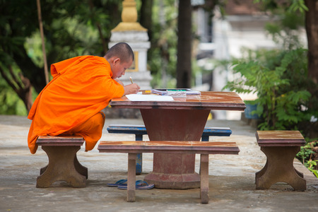 Luang Prabang , Laos - August 12 ; Young monk of Buddha studying tripitaka on stone table in temple Luang Prabang on August 12 , 2015 . Luang Prabang , Laosのeditorial素材