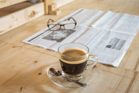 Cup of coffee with newspaper and glasses on tableの写真素材
