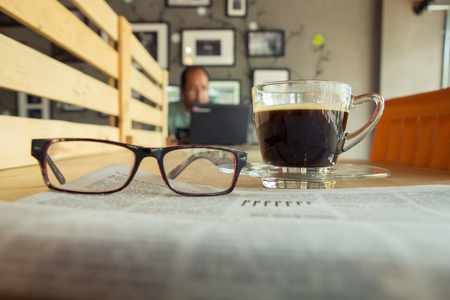 Cup of coffee on table in cafe with newspaper forgroundの写真素材