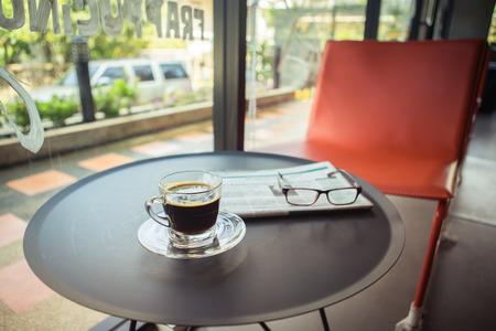Cup of coffee one table with newspaper and glasses . vintage style picture with low keyの写真素材
