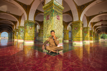 Mandalay-Myanmar,Dec 9 ; Staff protect of Golden Mahamuni Buddha Temple sitting smoking cigarette on Amazing architecture of Buddhist Temples at Mandalay on December 9,2015 . Manyday Myanmarのeditorial素材