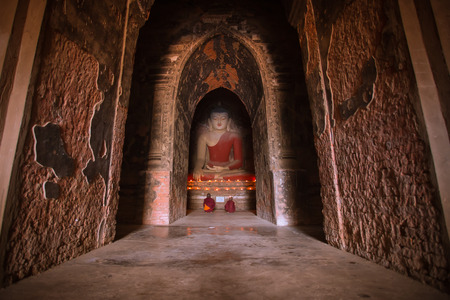 BAGAN, MYANMAR - Dec 12: Monk is praying with candles in front of Buddha statue inside pagoda on Dec 12, 2015 in Bagan. Monks with light and Buddha are highlighted of Baganのeditorial素材