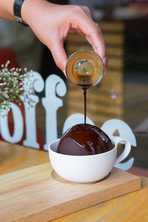 Affogato coffee flowing to chocolate ball cover ice cream in the cupの写真素材