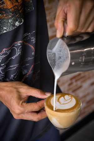 Pouring milk making latte art on cup of coffeeの写真素材