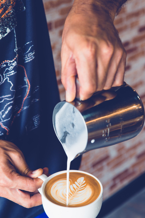 Pouring milk making latte art on cup of coffeeの写真素材