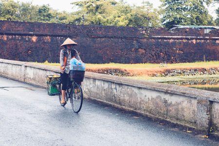 Hue, Vietnam -NOVERBER 06, 2016: Vietnamese woman riding the bicycle in front of the Imperial Citadel on November 06, 2016 in Hue, Vietnam.のeditorial素材