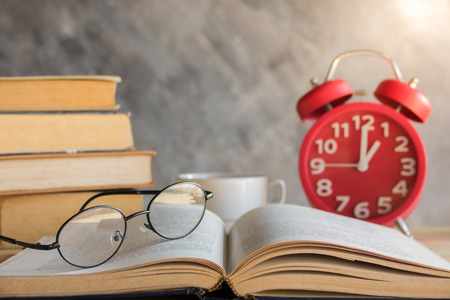Reading glasses on old book with alarm clockの写真素材