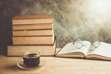 Black coffee on table with stack old books and glassesの写真素材
