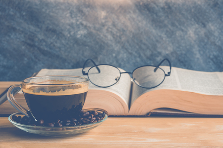a cup of freshly coffee on a table with booksの写真素材