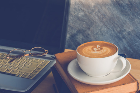 Personal laptop computer with cup of coffee of stack booksの写真素材